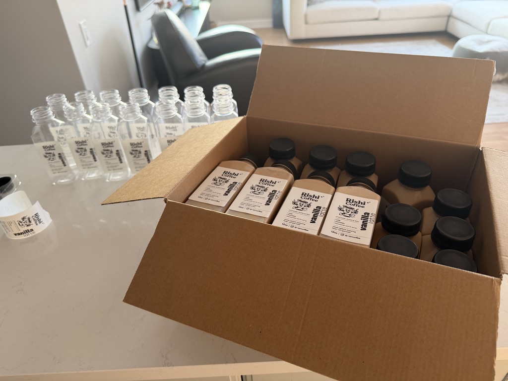 A box of finished bottles next to empty labeled bottles waiting to be filled