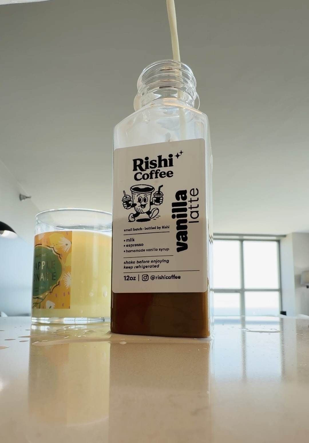 Milk being poured into a labeled bottle of espresso